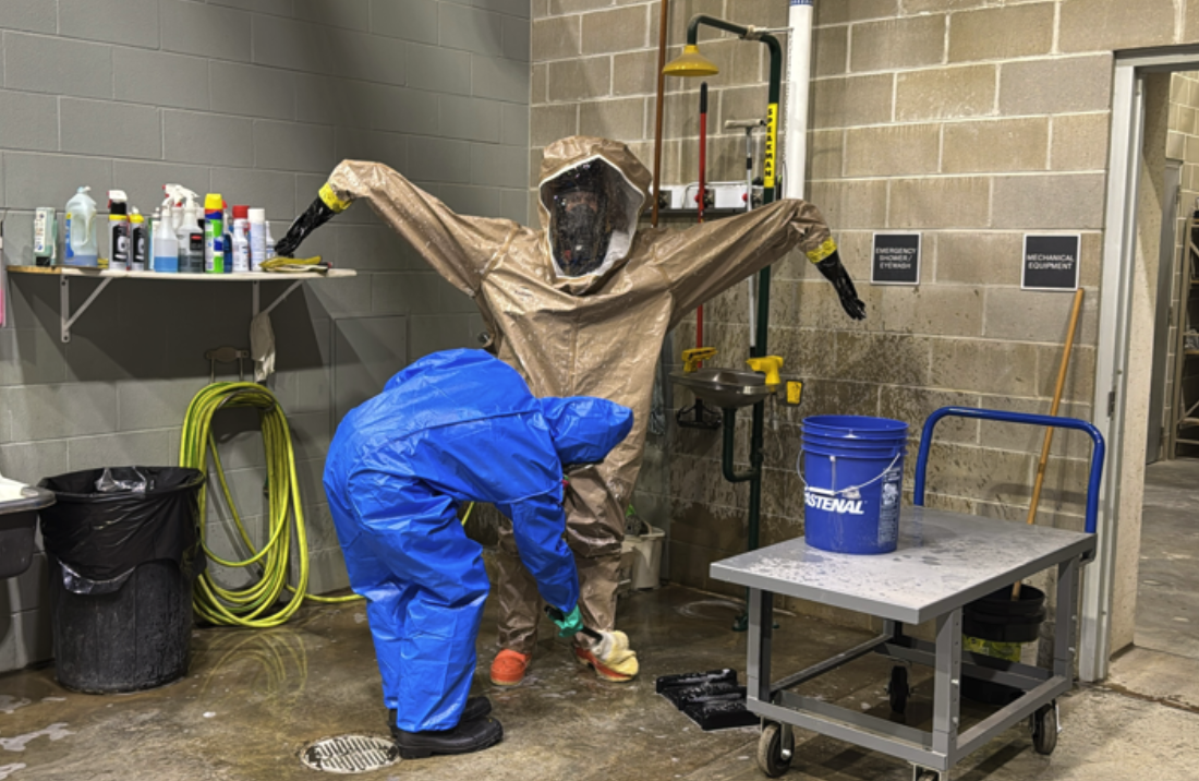 TIS water purification training includes suiting up and cleaning co-workers of hazardous materials